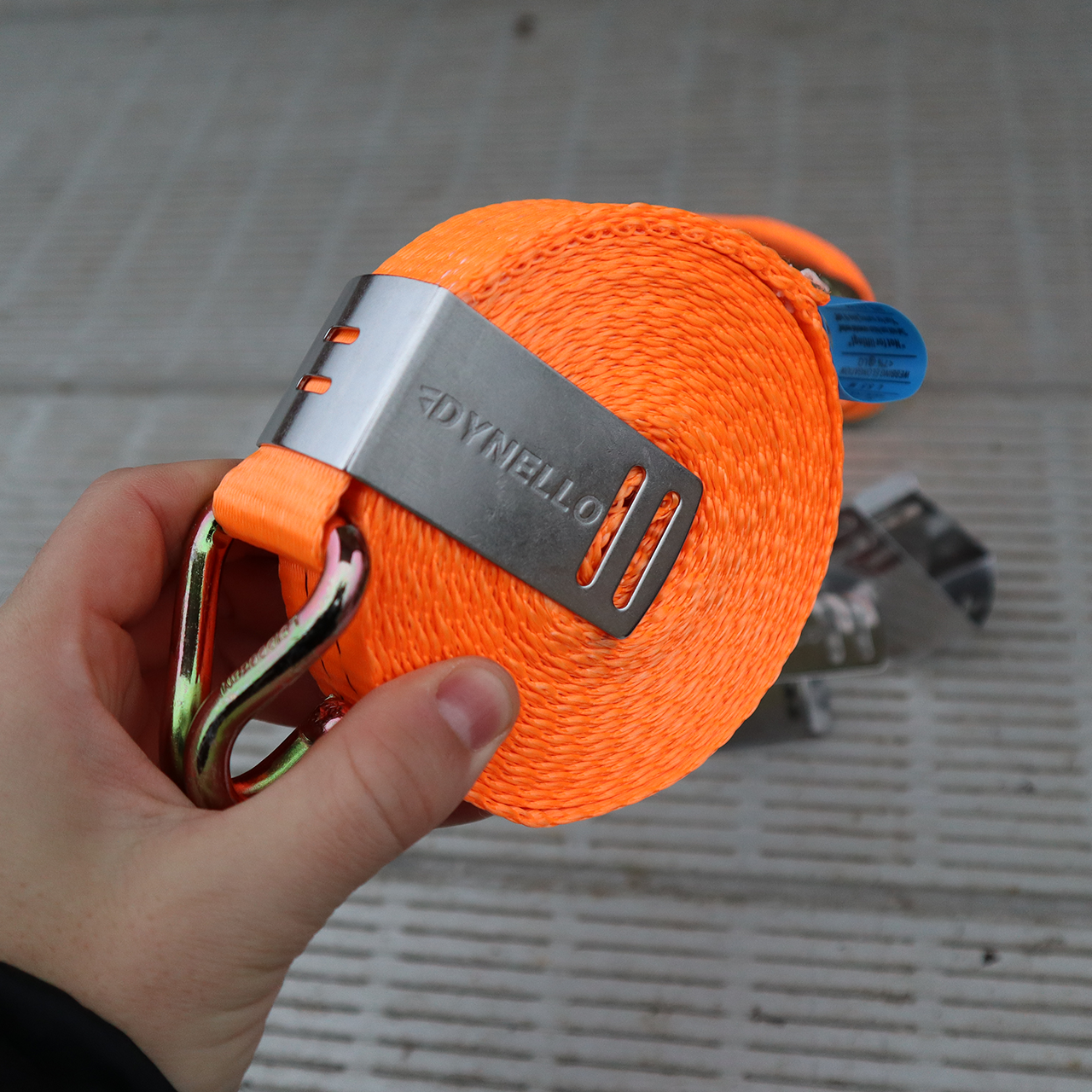 Dynello 35mm Strap Clip (6 pack), stainless steel, shown in hand holding a coiled strap, ideal for organizing and preventing strap tangling.